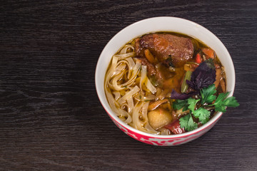 A plate of hot oriental soup with meat and noodles