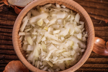 close up of finely chopped diced onion in wooden dish background