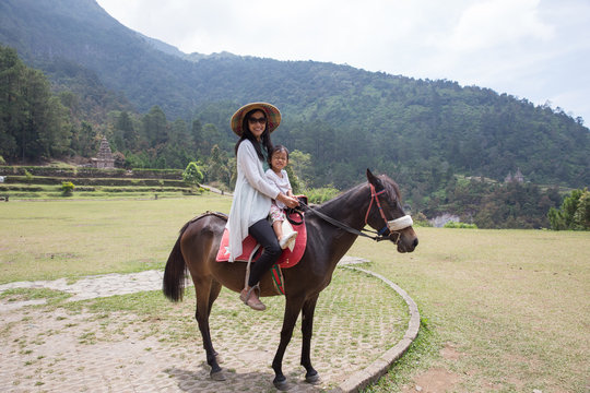 Kid with mum drive on horse top