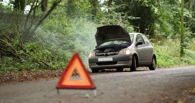 4K Broken down car with smoking engine left abandoned on quiet country road. No people.