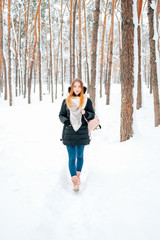 Fototapeta na wymiar Attractive blond young adult woman walking through winter forest