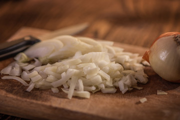 close up of finely chopped diced onion in wooden dish background