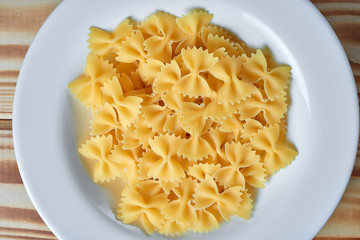 Macaroni in a plate on a wooden background