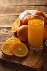 Glass of orange juice, sliced orange, orange on the wooden background