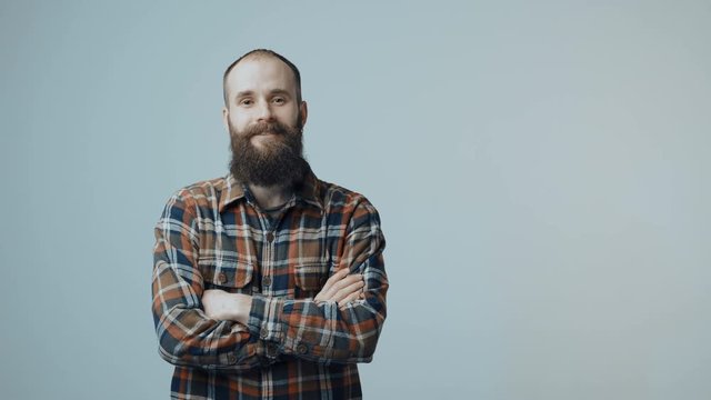 Bearded man entering in frame, standing smiling at camera with folded hands and then gesturing thumb up sign