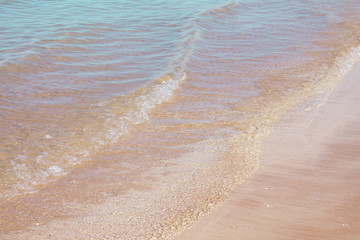 Fototapeta na wymiar Yellow warm sand and sea wave of the ocean. Summer beach background.
