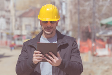 Construction worker posing with his tablet outdoors.