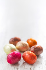 Small chocolate Easter eggs on a rustic white background