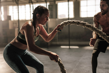 Young woman working out with battle ropes - obrazy, fototapety, plakaty