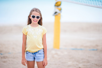 Little adorable girl playing beach volleyball. Sporty family enjoy beach game outdoors