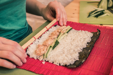 Obraz na płótnie Canvas A woman is making rolls on a red mat
