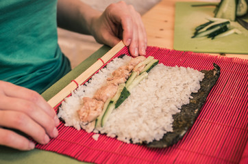 A woman is making rolls on a red mat