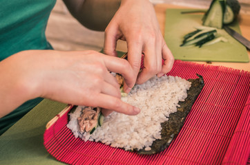 A woman is making rolls on a red mat