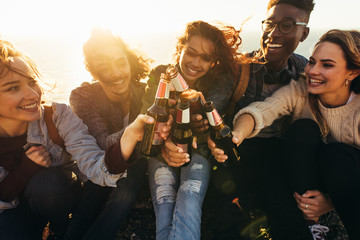 Multi-ethnic group of people toasting beers outdoors - obrazy, fototapety, plakaty