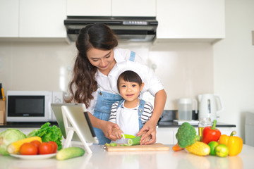 Happy family in the kitchen. Mother and child daughter are preparing the vegetables and fruit.