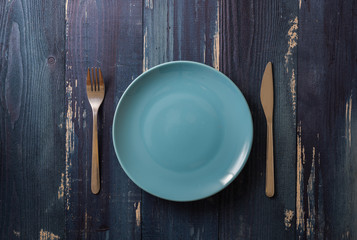 Blue Plate on blue wooden background with utensils