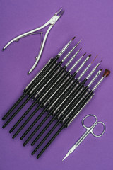 top view of nail nippers, brushes and scissors isolated on purple
