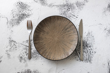 Plate on white wooden background with utensils