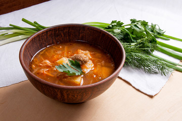 Borsch - traditional Ukrainian and Russian red beetroot soup with red beets in clay bowl on wooden background..
