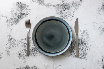 Plate on white wooden background with utensils