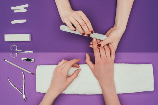 cropped image of manicurist filing nails with nail file