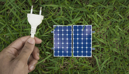 Solar panel and holding a power plug on the grass. Solar Energy Concept Image. 