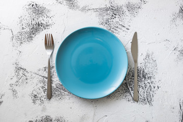 Blue Plate on white wooden background with utensils