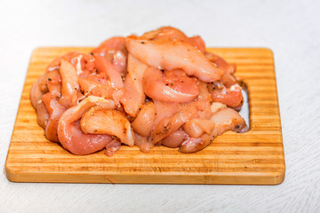 Raw chicken fillet with spices on wooden board