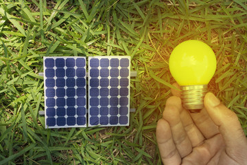 Solar panel and holding yellow lamp on the grass. Solar Energy Concept Image. 
