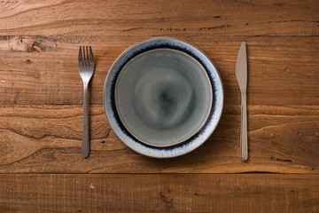Plate on brown wooden background with utensils