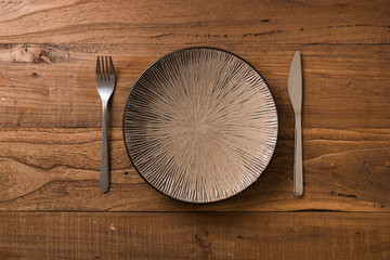 Plate on brown wooden background with utensils