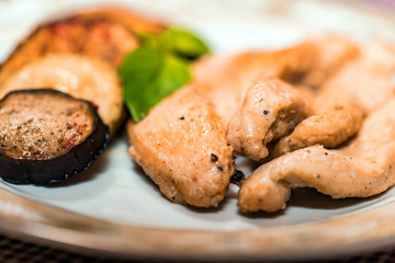 Pieces of roasted chicken and vegetables on plate