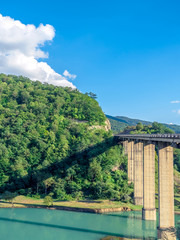 Fototapeta premium bridge above calm turquoise river in georgian mountains