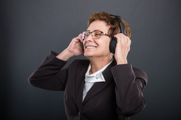 Portrait of business senior lady enjoying listening to headphones