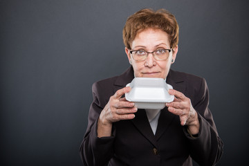 Portrait of business senior lady smelling lunch box