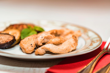 Pieces of roasted chicken and vegetables on plate