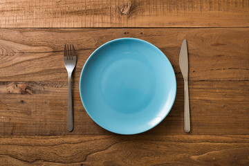 Blue Plate on brown wooden background with utensils