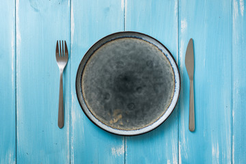 Plate on blue wooden background with utensils