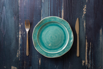 Turquoise Plate on blue wooden background with utensils
