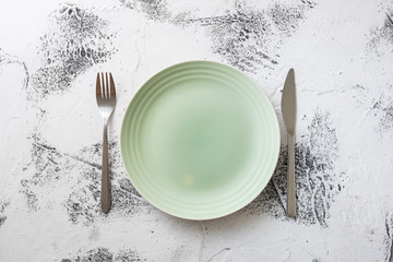 Green Plate on white wooden background with utensils