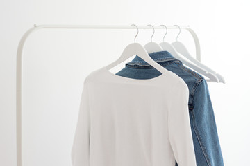 Jeans jacket and a white shirt weigh on a white clothes hanger