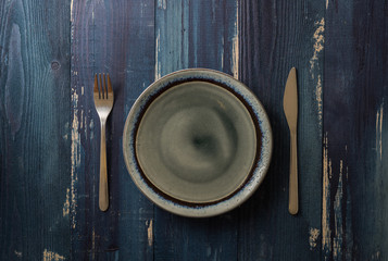 Plate on blue wooden background with utensils