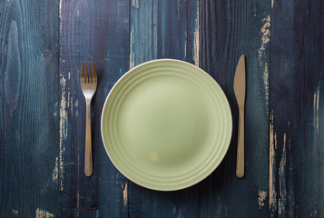Green Plate on blue wooden background with utensils