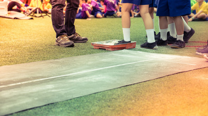 Students boy prepare for long jump competition at school sports day by put legs on chalk or lime powder. School sports day competition concept.