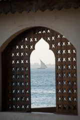 Traditional dhow boat sailing on the sea, seen through the window at sunset, Zanzibar