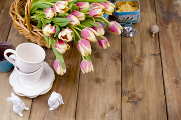 Beautiful bouquet of fresh spring flowers. Tulips. Wooden brown background. Cups for tea and white rabbit. Free space for text or a postcard.