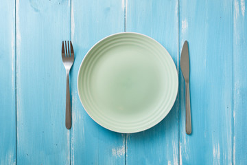 Green Plate on blue wooden background with utensils