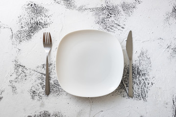 White Plate on white wooden background with utensils