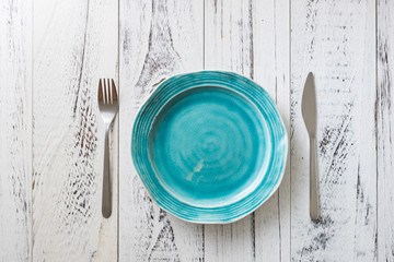 Blue Plate on white wooden background with utensils