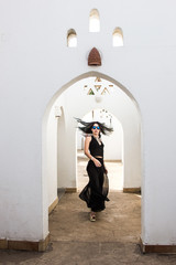 beautiful girl in sunglasses looking at camera while running at white building in Egypt